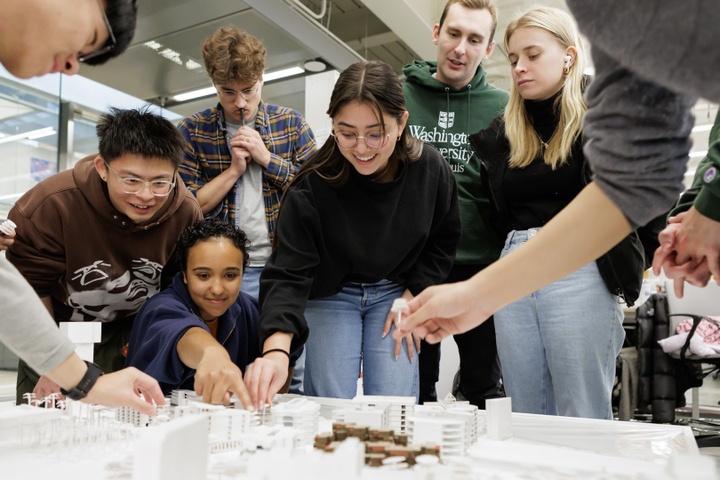 Group of students gathers around a tabletop model of a city.