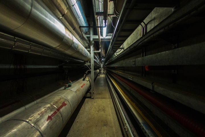 Darkened area featuring large metal tubes and a concrete walkway