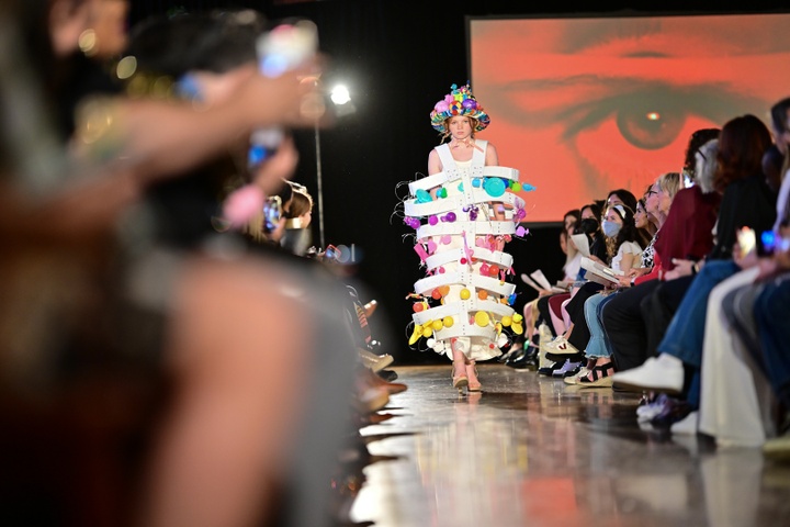 A model walking down the runway in a white cage-style dress with balloon details