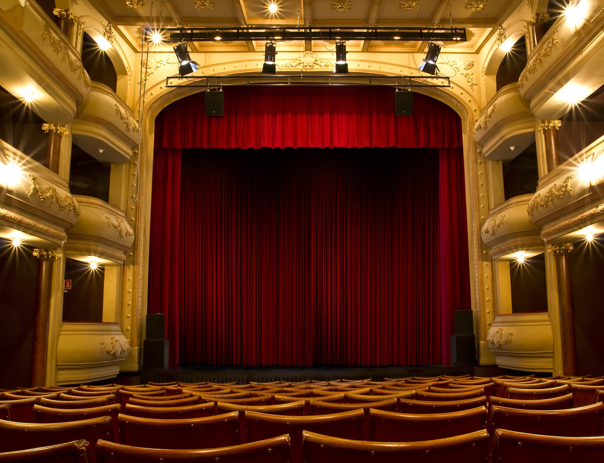 A frontal view of a drawn red proscenium stage curtain