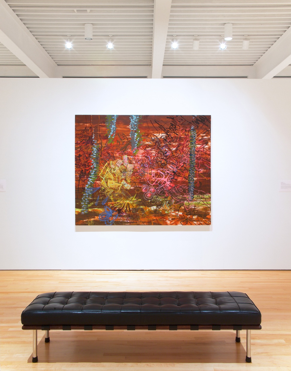 A black leather bench in front of a large, bright abstract painting hung on a while wall.