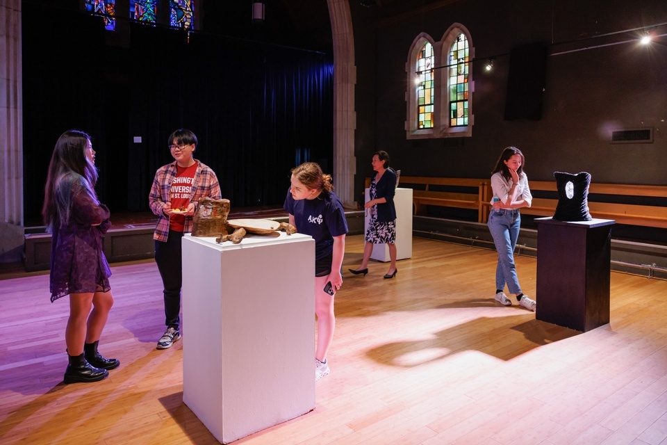 People look at sculptures on plinths in a converted chapel.