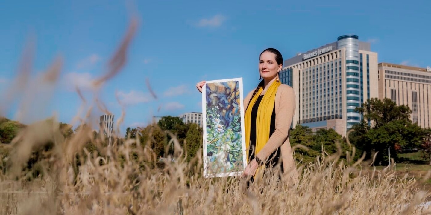 photo of a woman standing in a field holding a painting 