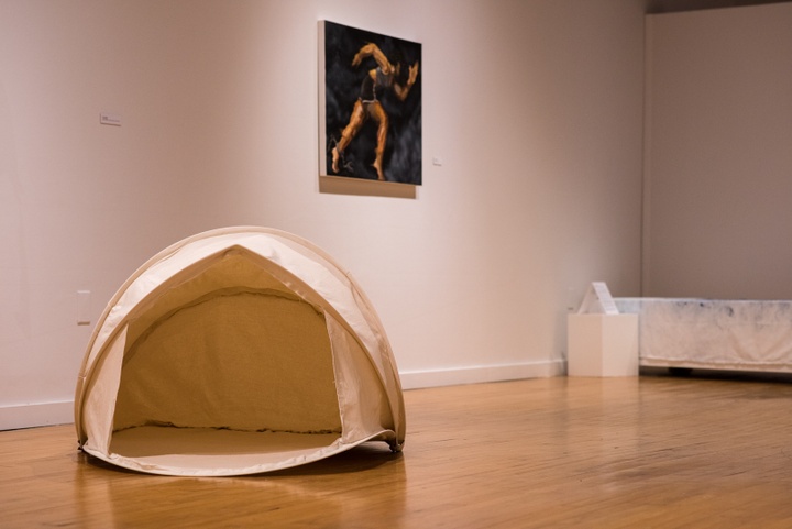 A handmade pup tent made of canvas sits on the floor.