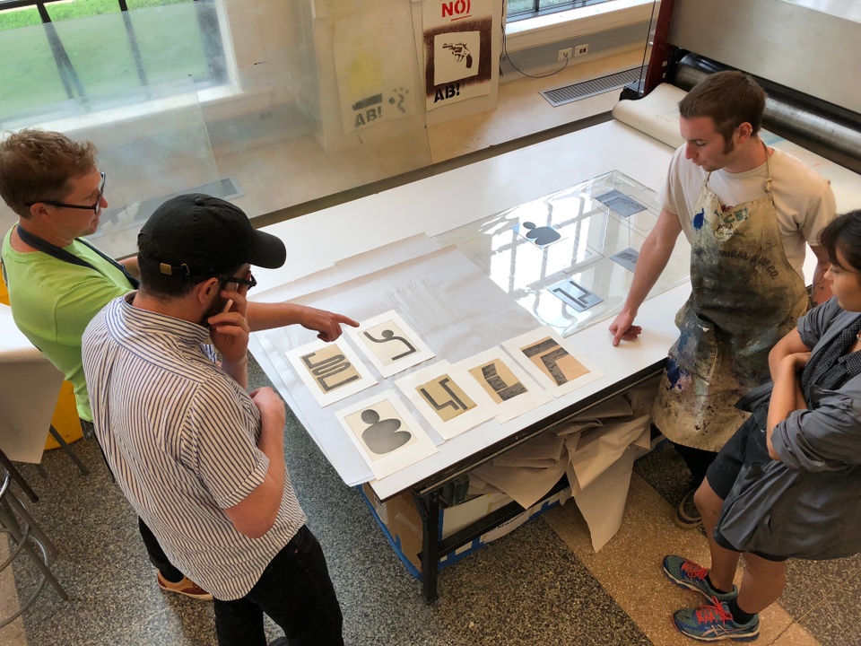 View from above of 4 people looking at prints just after printing.