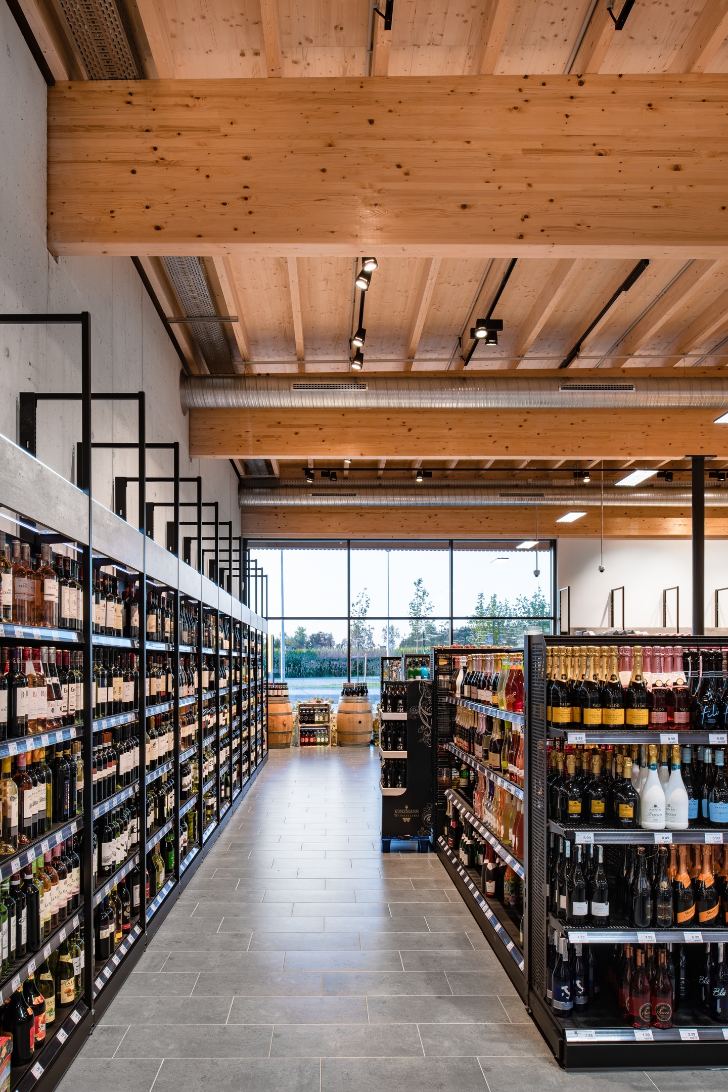 Interior of a supermarket with wooden roof beams and rustic wood and iron shelving units.