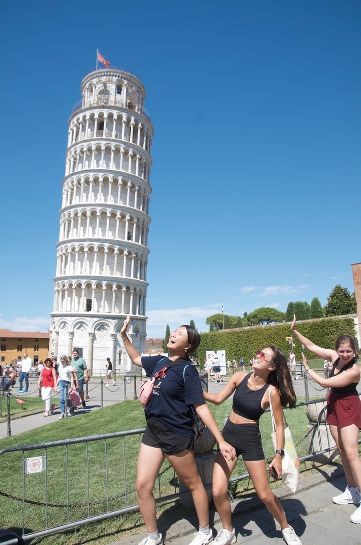three students pretending to hold up leaning tower of pisa
