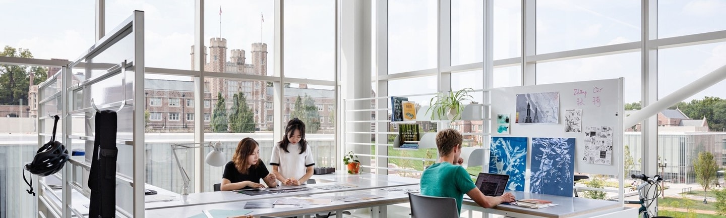 Three students work at large desks in the open, light-filled graduate architecture studios located in Weil Hall in WashU's Sam Fox School.