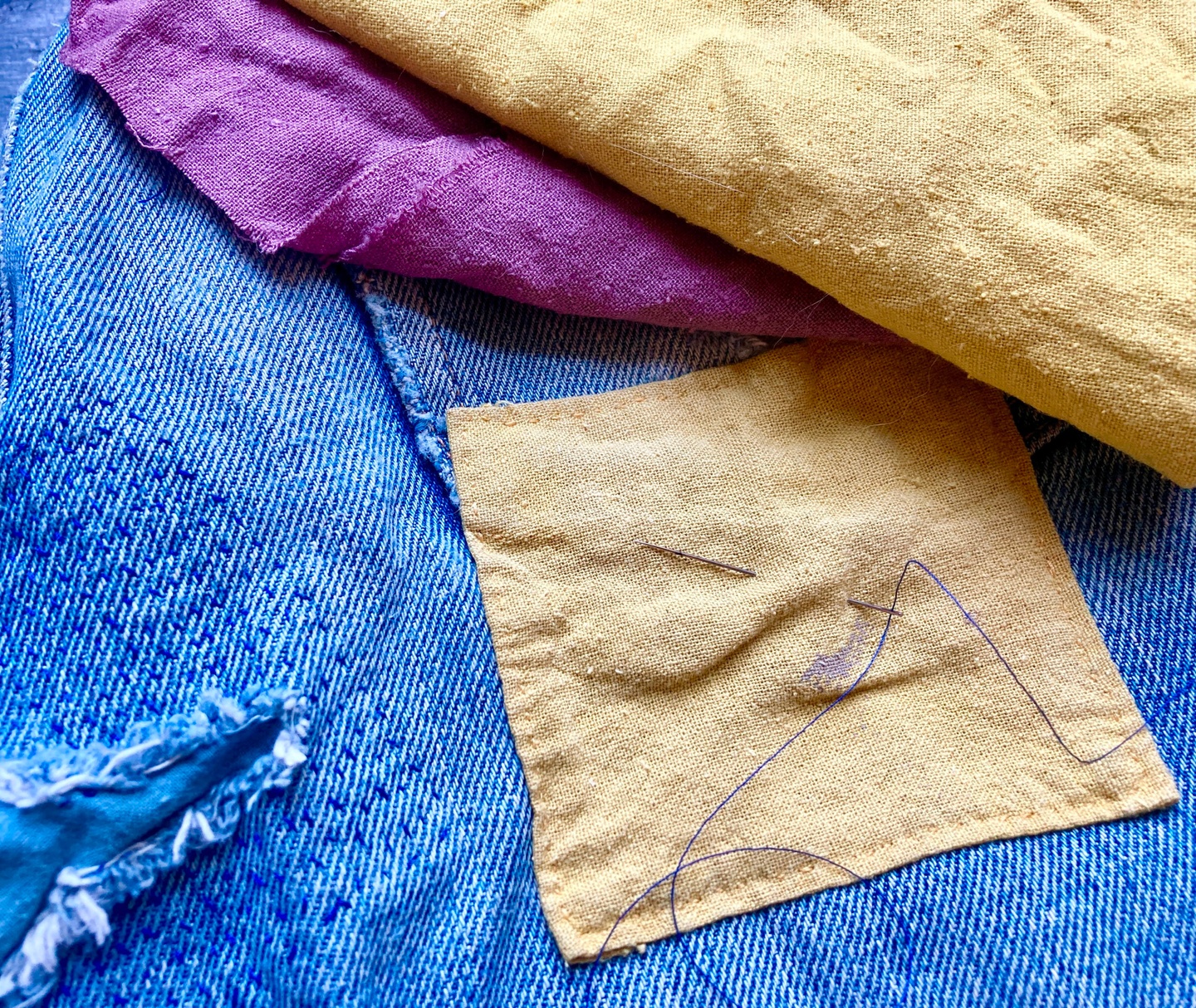 Scraps of denim, yellow, and purple mended fabric