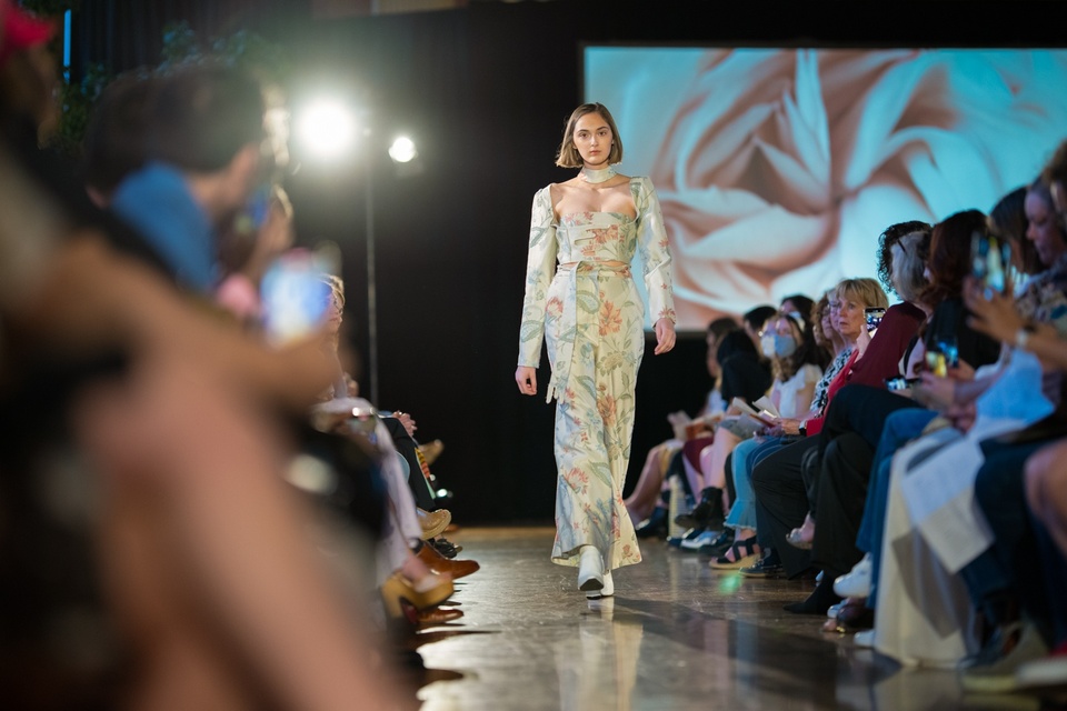 A model walking down the runway in a green floral long sleeves and pants