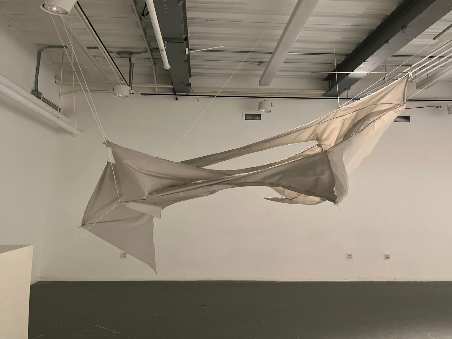 A white tarp with rips hanging fron the ceiling.