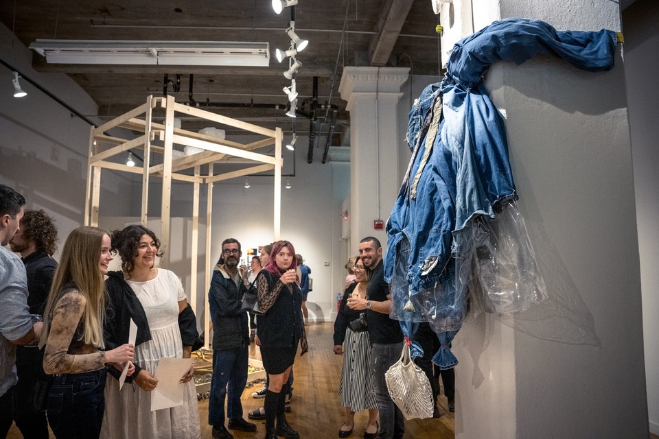 Gallery view with visitors in front of Karen Yung's large soft denim jacket dress sculpture hung on the wall