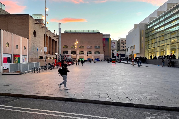 Woman walking in paved plaza at sunset in Barcelona.
