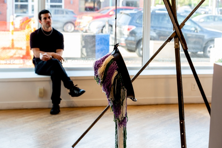 A student sits in front of a 3 legged tripod-like sculpture by Alex Davis