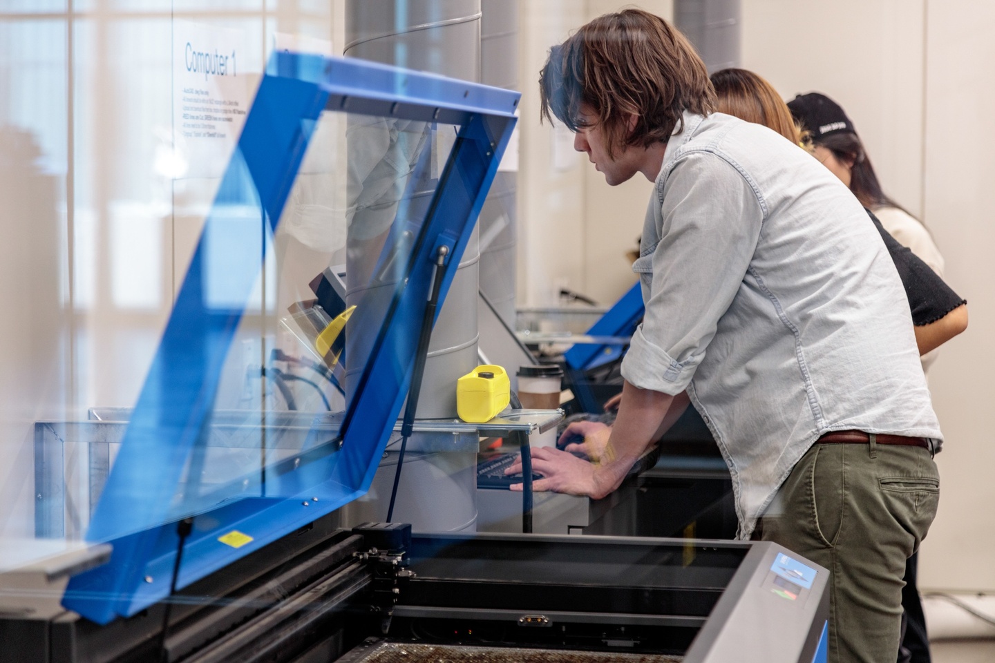 Instructional technician + students working on a large 3D printer.