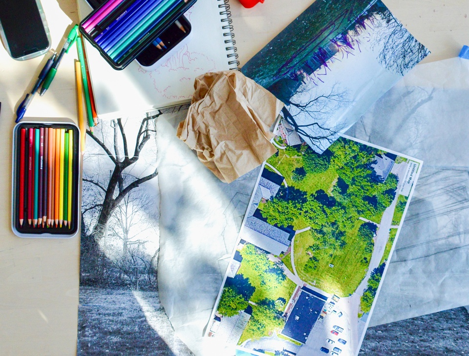 image of landscape photos, colored pencils, and other drawing materials on a table