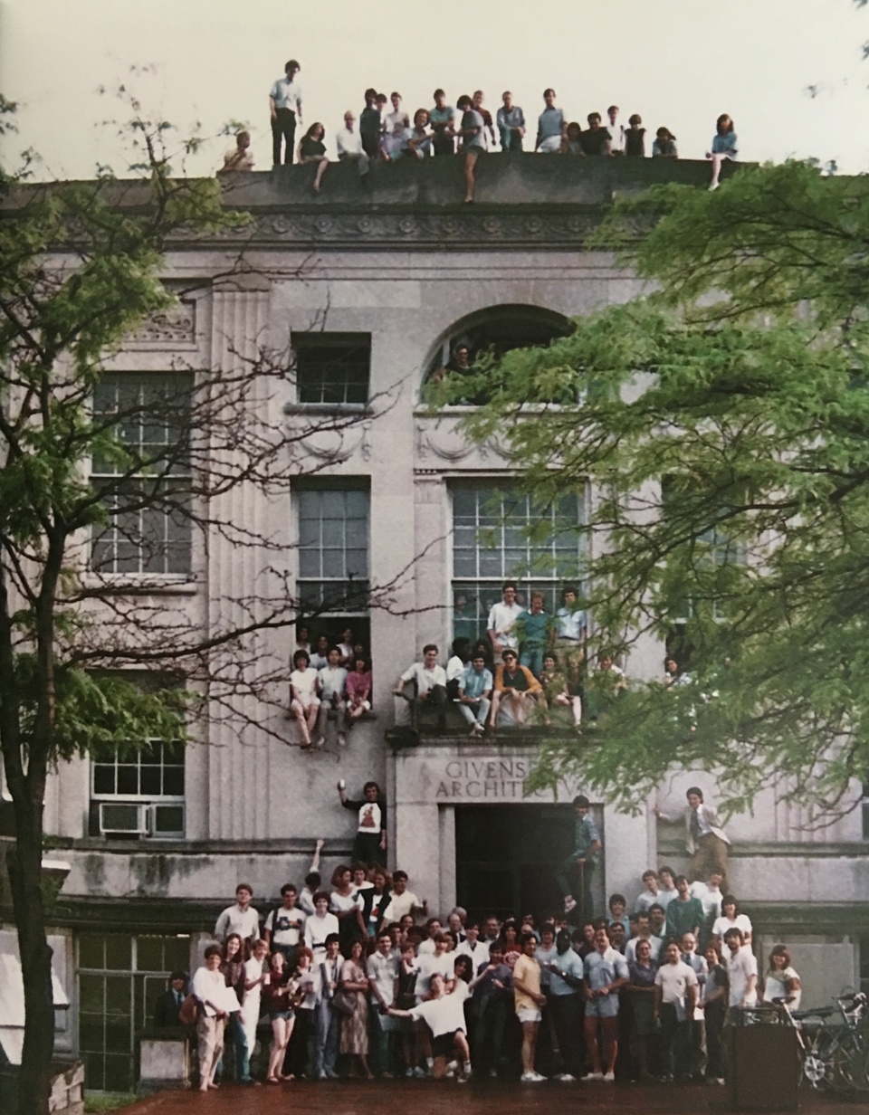 Beaux-arts building facade with groups of people posing on the ground, sitting on window ledges, and standing on the roof.