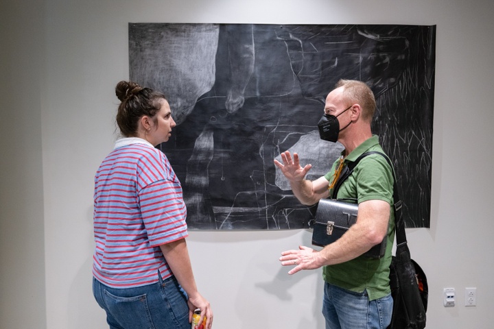 Arny Nadler in discussion with Samantha Kalson in front of her large charcoal abstract work