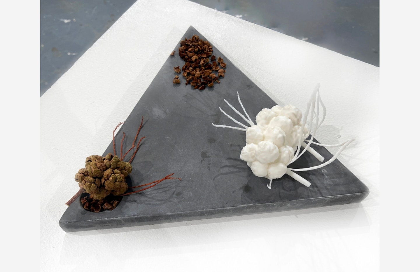 Sculpture of 3 abstract shapes in brown and white sitting on top of a gray triangle