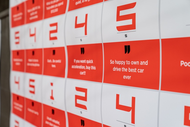 Close-up of red and white grid design. The white panels have large red numbers between 1-5. The red boxes have quotes, such as "So happy to won and drive the best car ever."