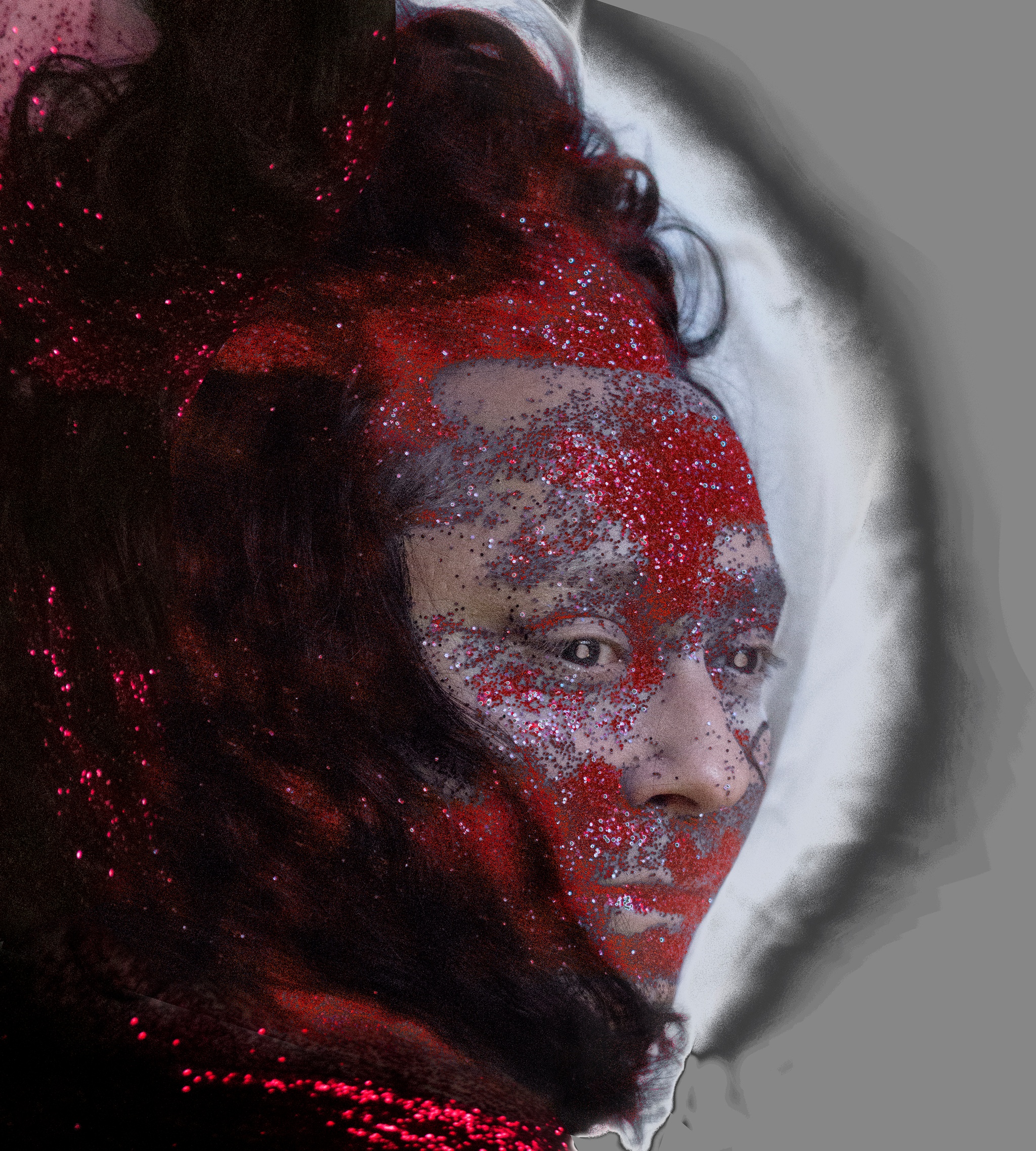 A close-up portrait of the artist ANOHNI with red glitter spread over her face and hair. She looks out to the left from her hair that falls over the side of her face. 