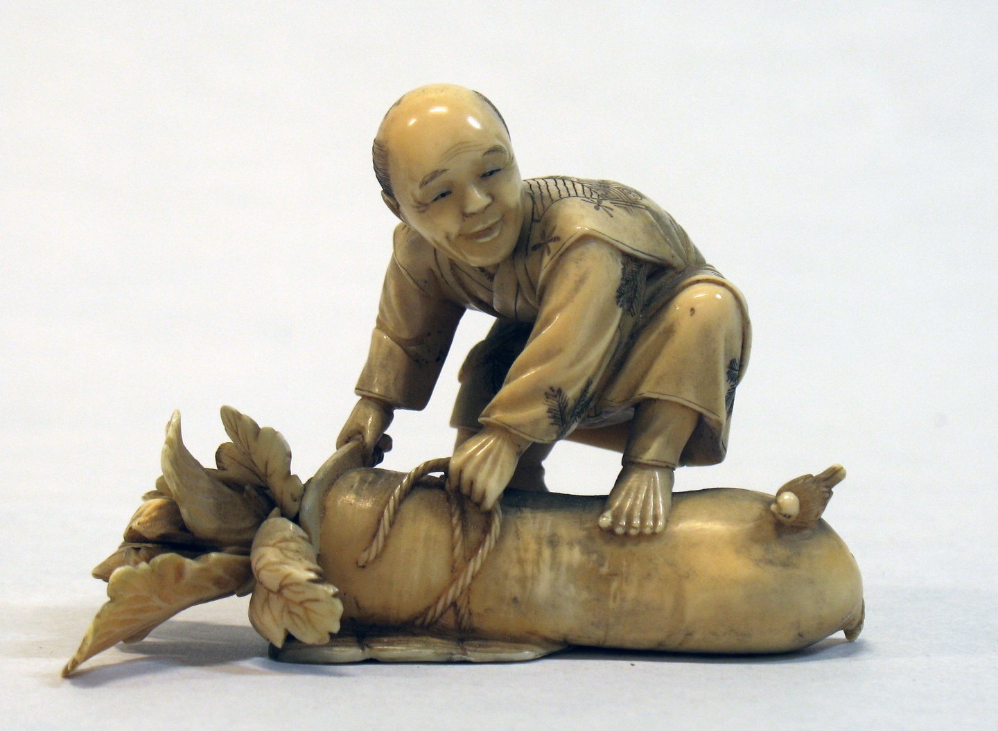 Small ivory carved sculpture of a figure holding a rope and chopping a log