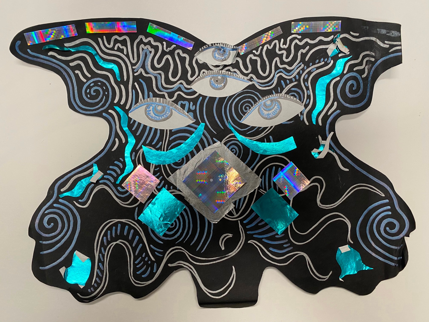 A black abstract symmetrical form with multiple eyes and pops of blue and metallic colors.