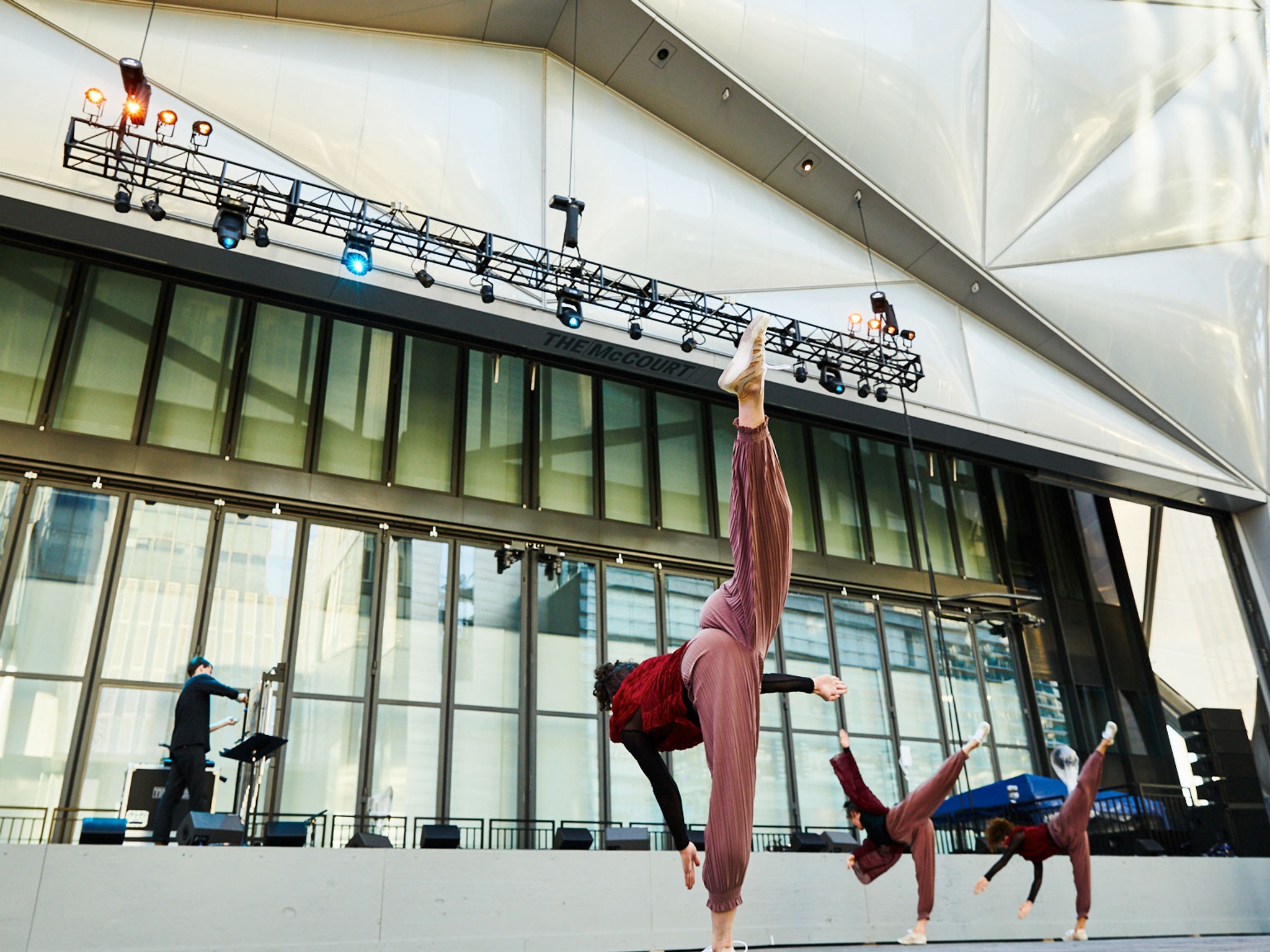 Three dancers doing a standing split kick.