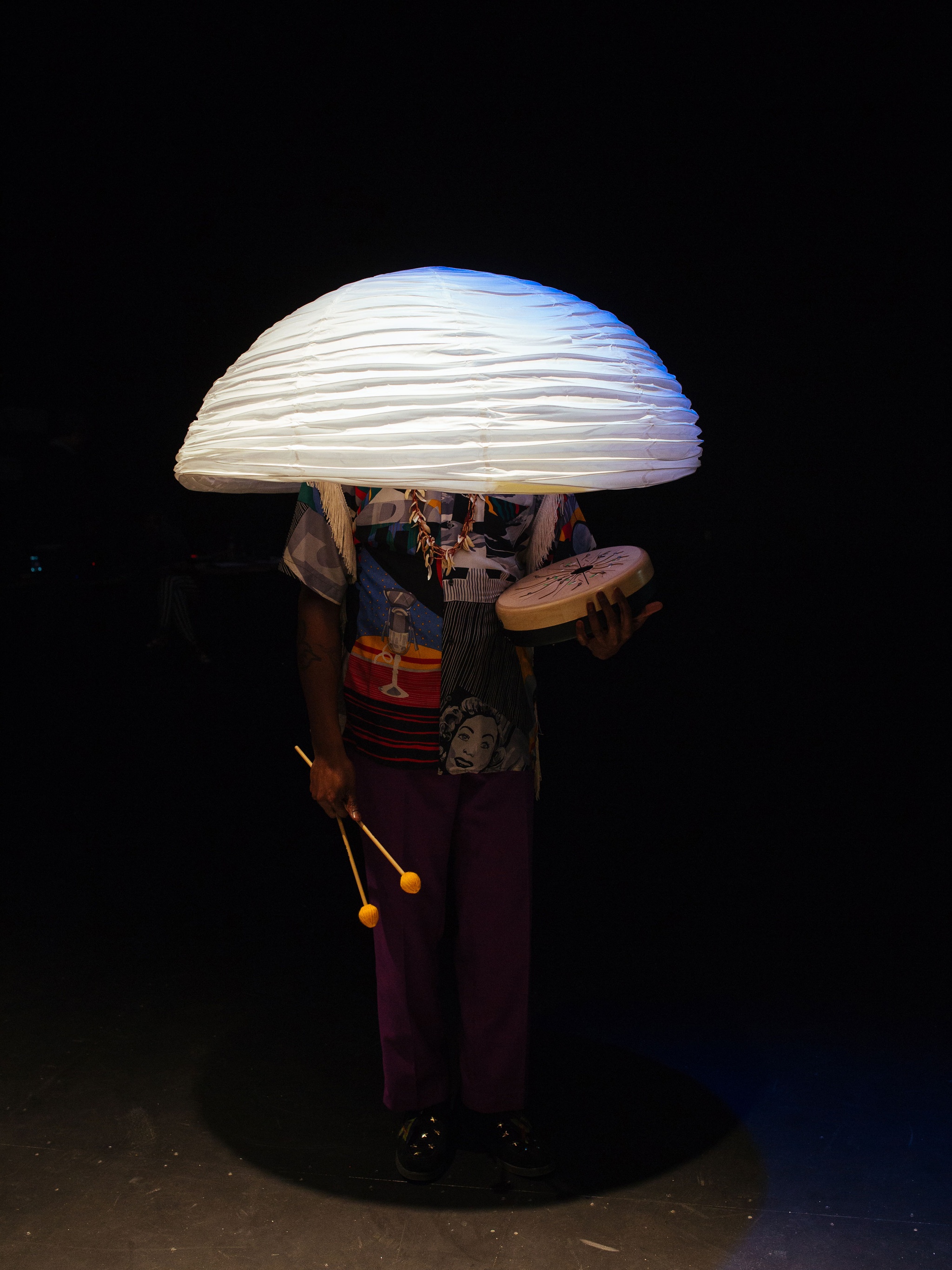 Person under mushroom-like crepe object covering their upper face.