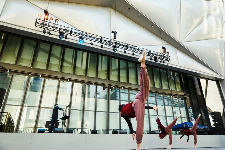 Three dancers in motion on an outdoor stage.