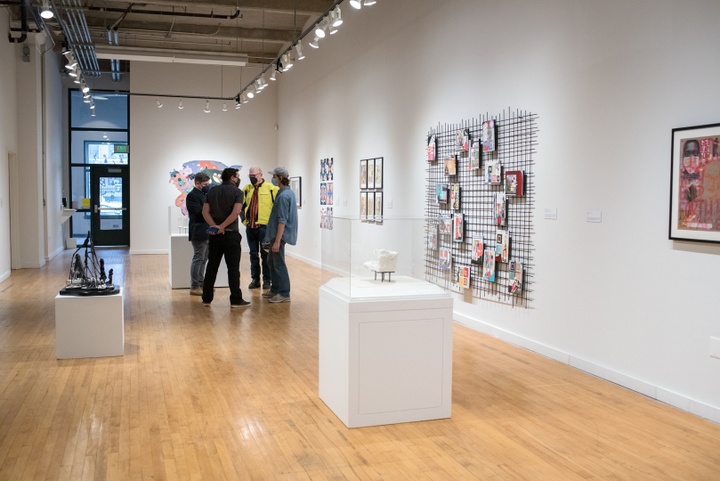 Gallery space with a group of people talking in the background.