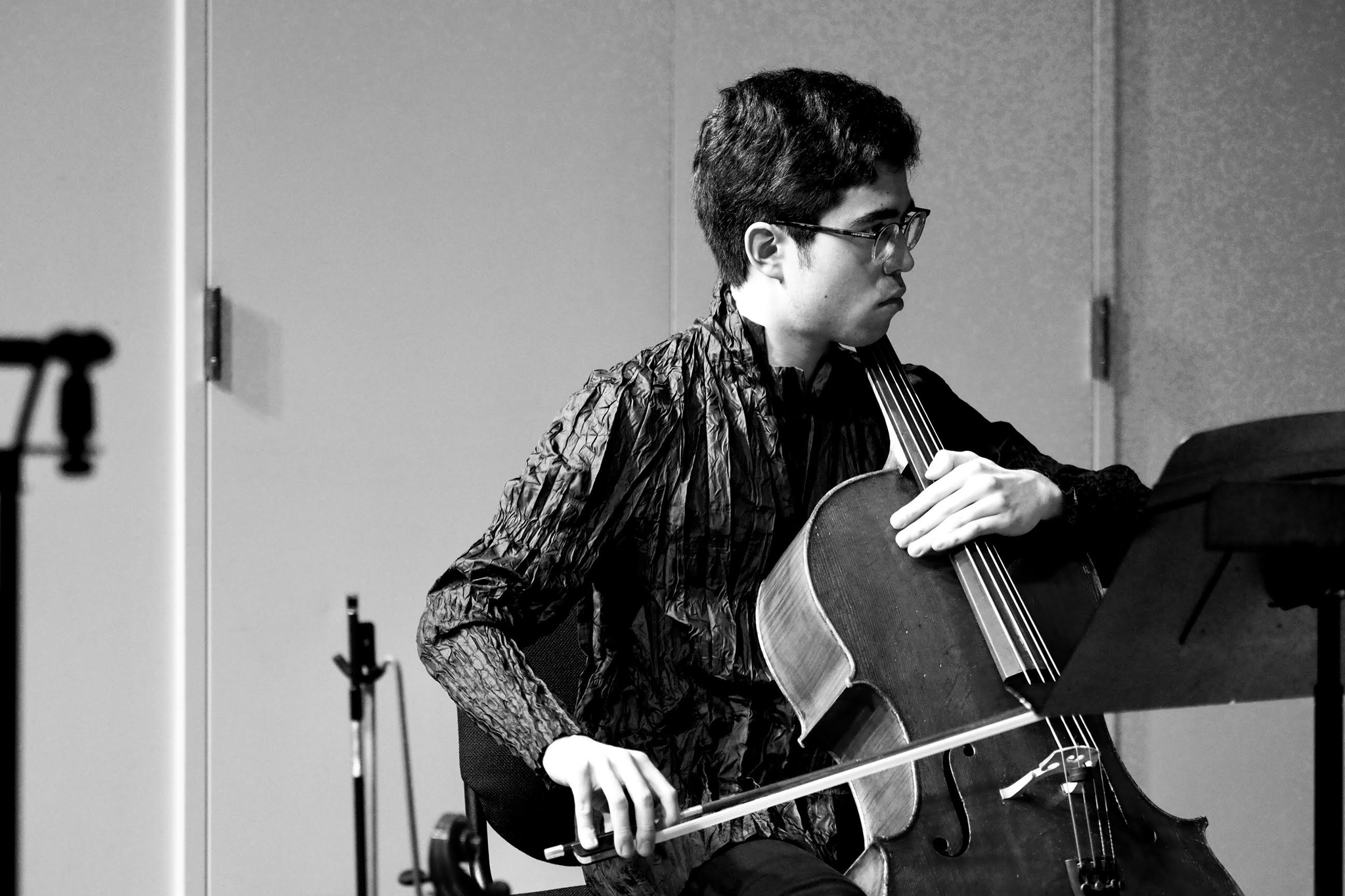 A cellist seen from the side playing his instrument