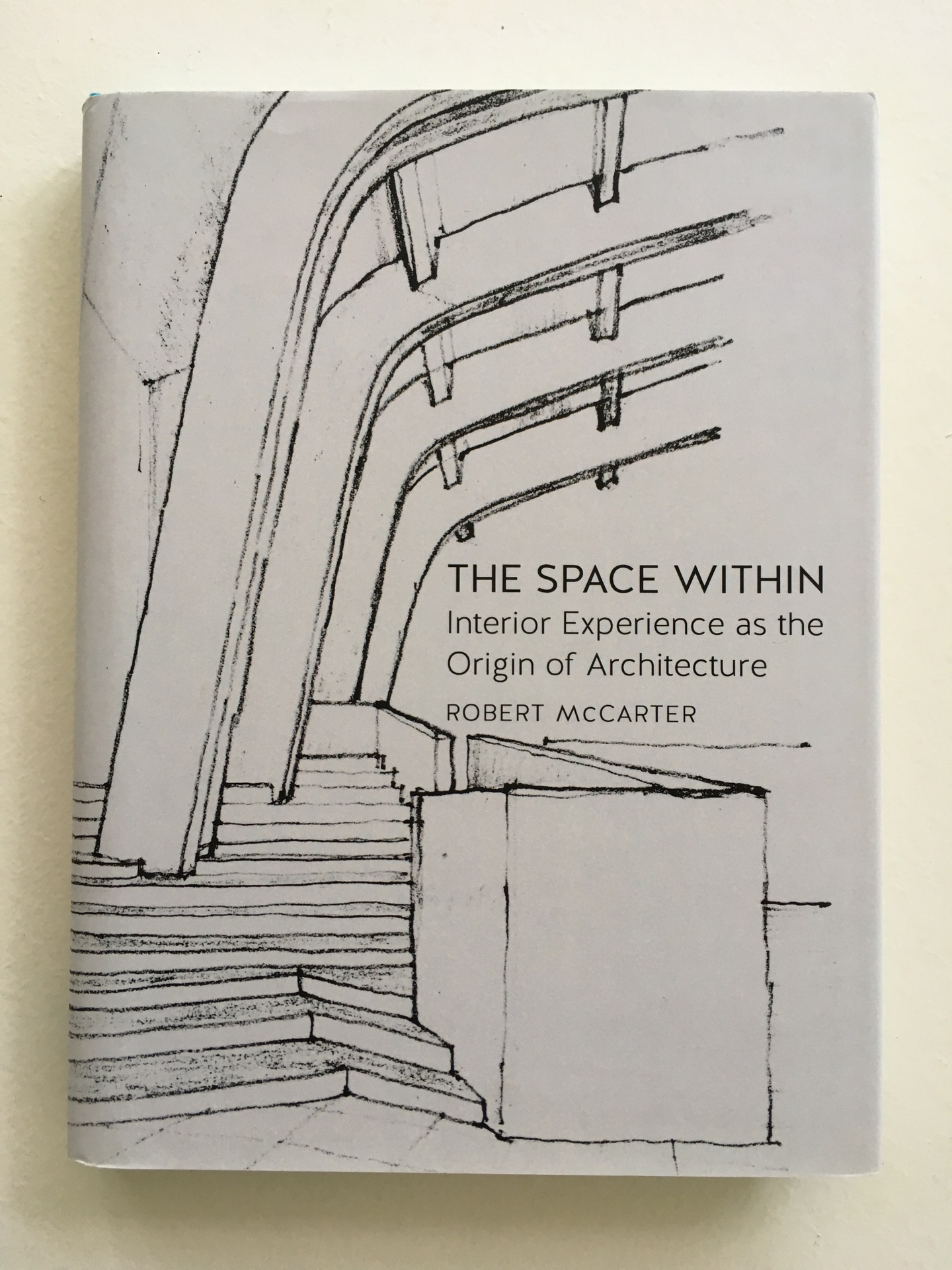 Cover of The Space Within, with a black-and-white drawing of an interior space with steps and a curved ceiling.