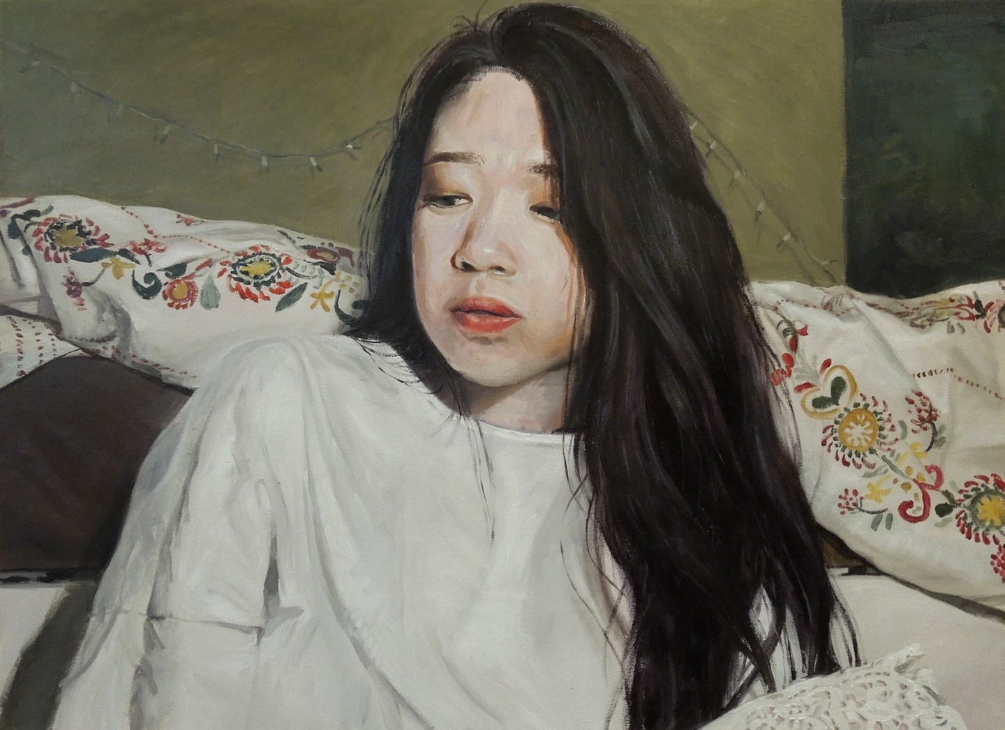 Painted portrait of a person with long dark hair in a white loose shirt, from the chest up, sitting on a bed with a white embroidered comforter, with their gaze cast down.