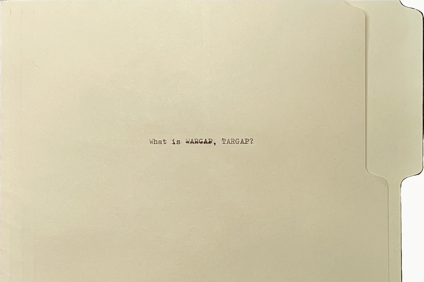 A manila folder on its side, with small, typewriter-written text that says "What is WARGAP, TARGAP?" The word WARGRAP is set in strikethrough type.