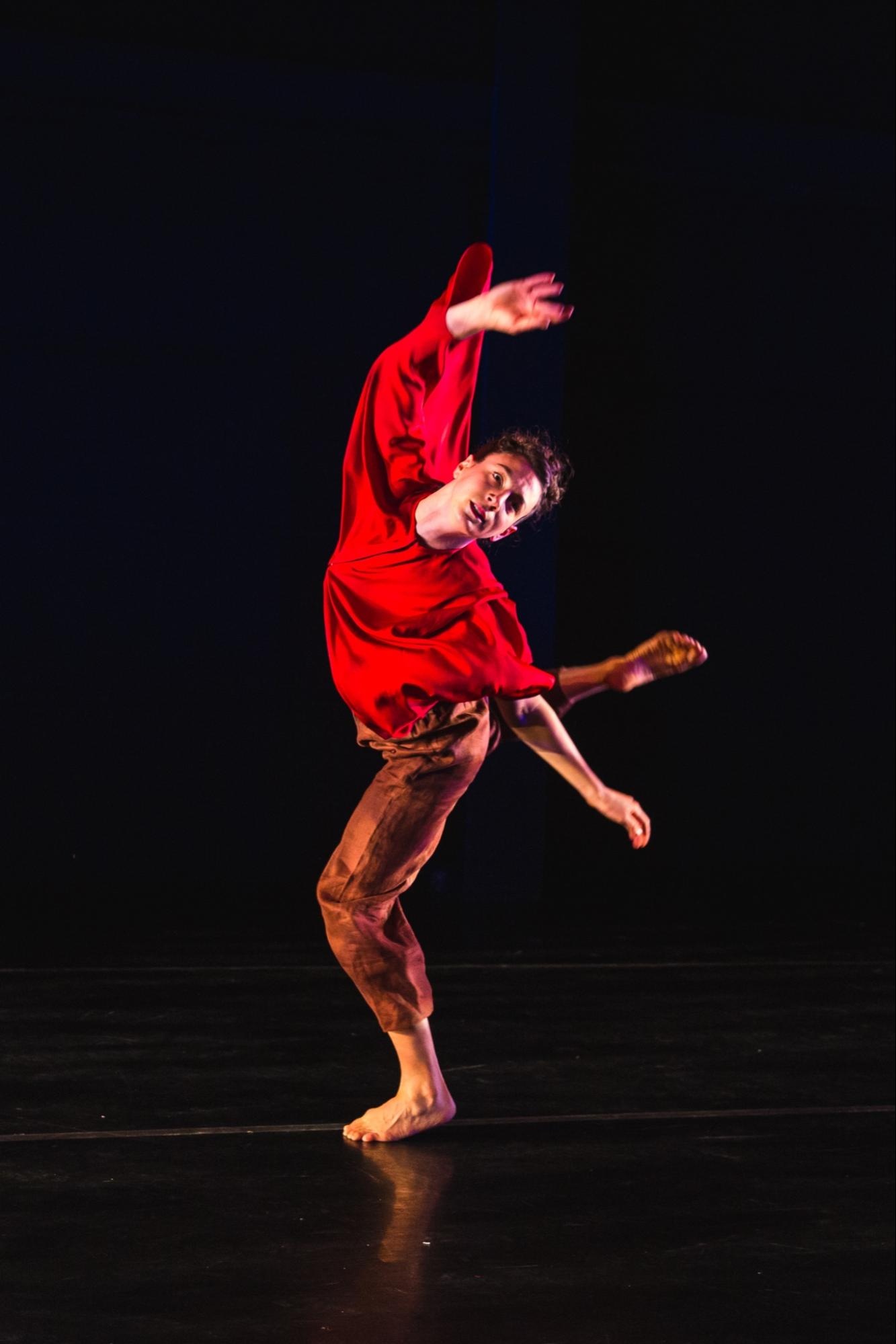 image4.jpgA dancer arching backward with only her bare left foot on the ground. Her hands are outstretched and she wears a red shirt and brown pnts. 