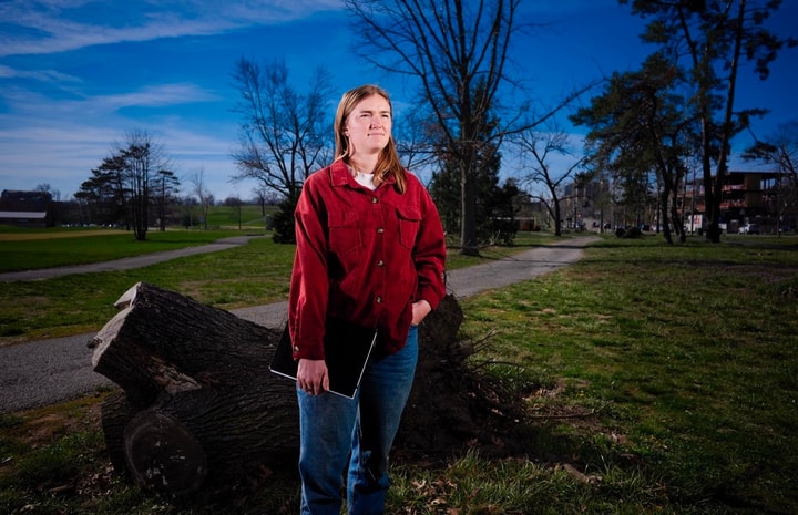 portrait of Amanda Kesler in a red button down shirt and jeans standing in Forest Park