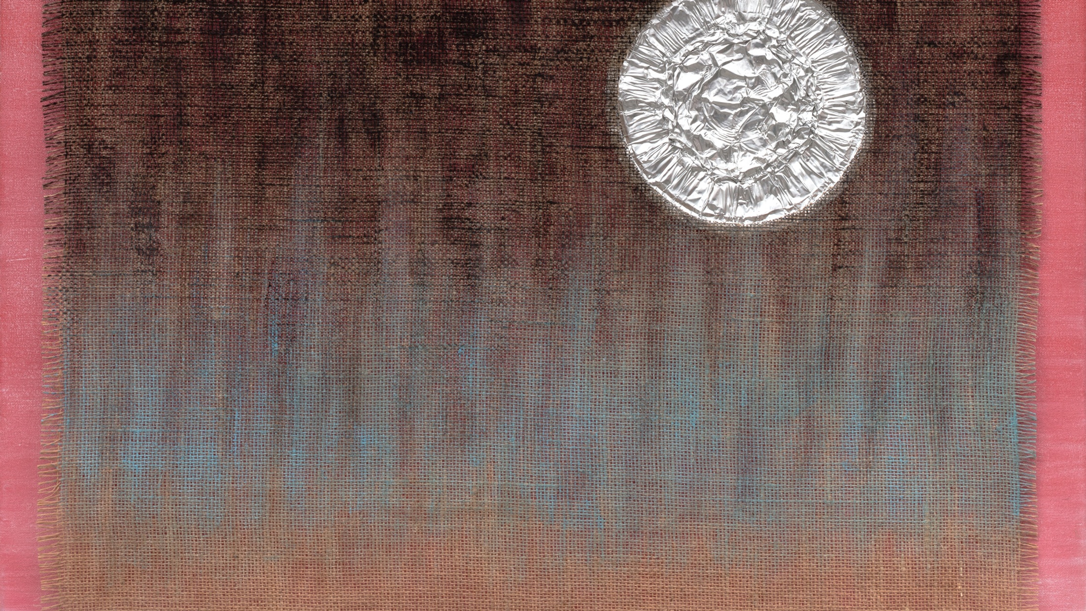 A silver circle sits on muslin, painted dark brown and blue, that lays atop a red canvas that is visible on the left and right edges.