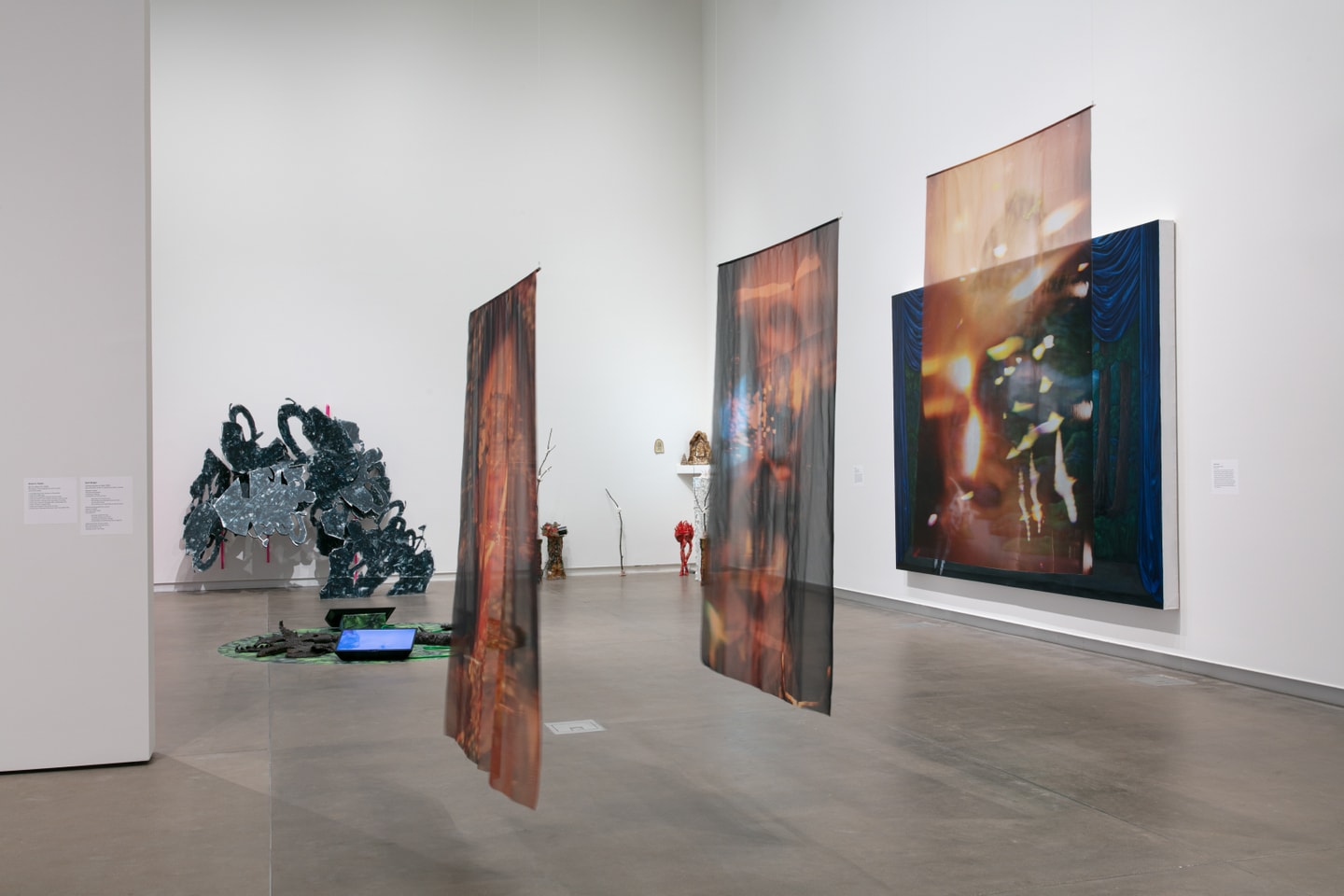 3 large scale photo prints on fabric hanging from the ceiling in a gallery