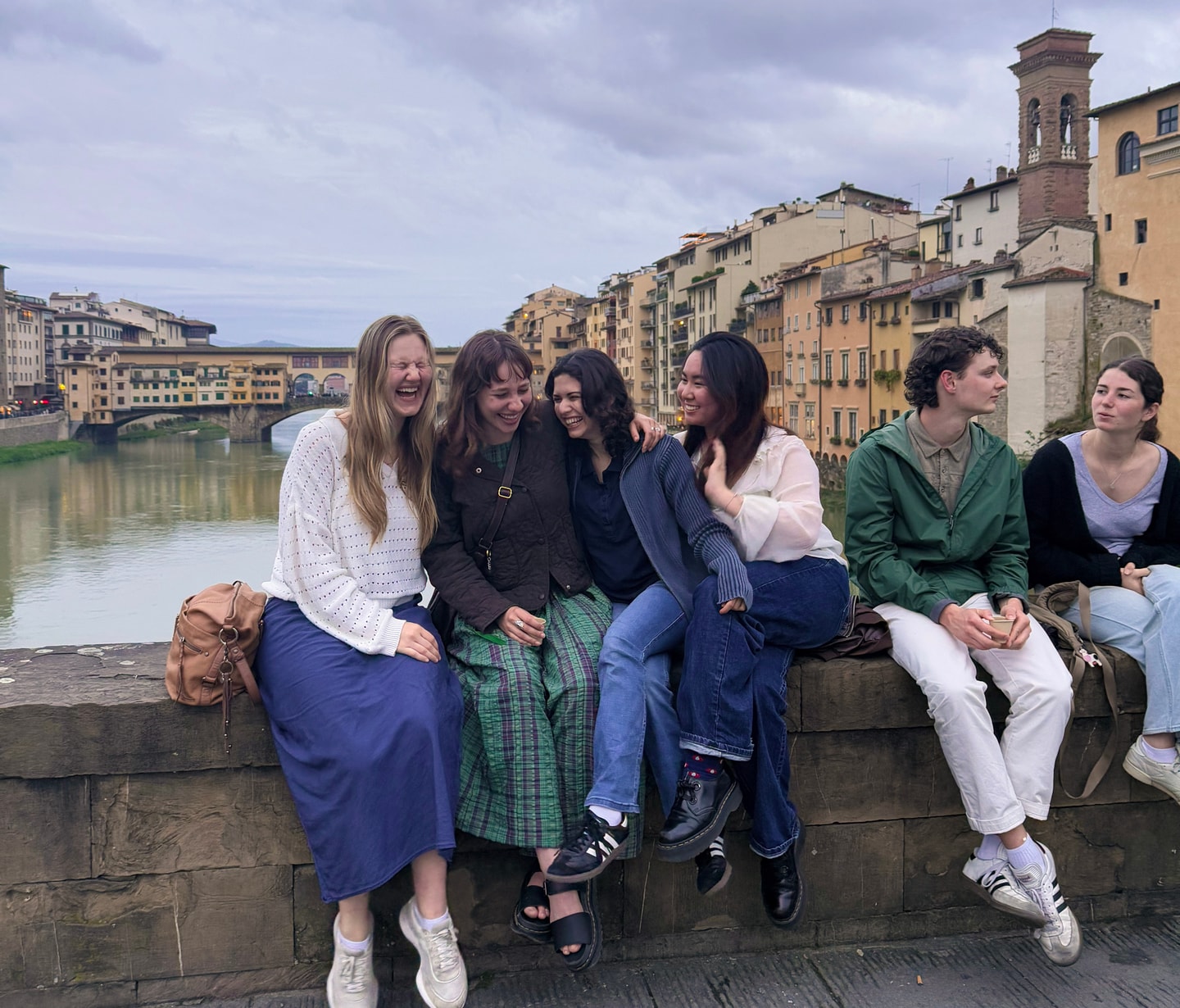 students still on bridge over Arno river, city in background