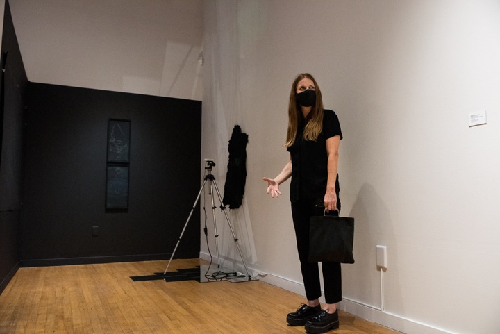 An artist stands in front of her installation work