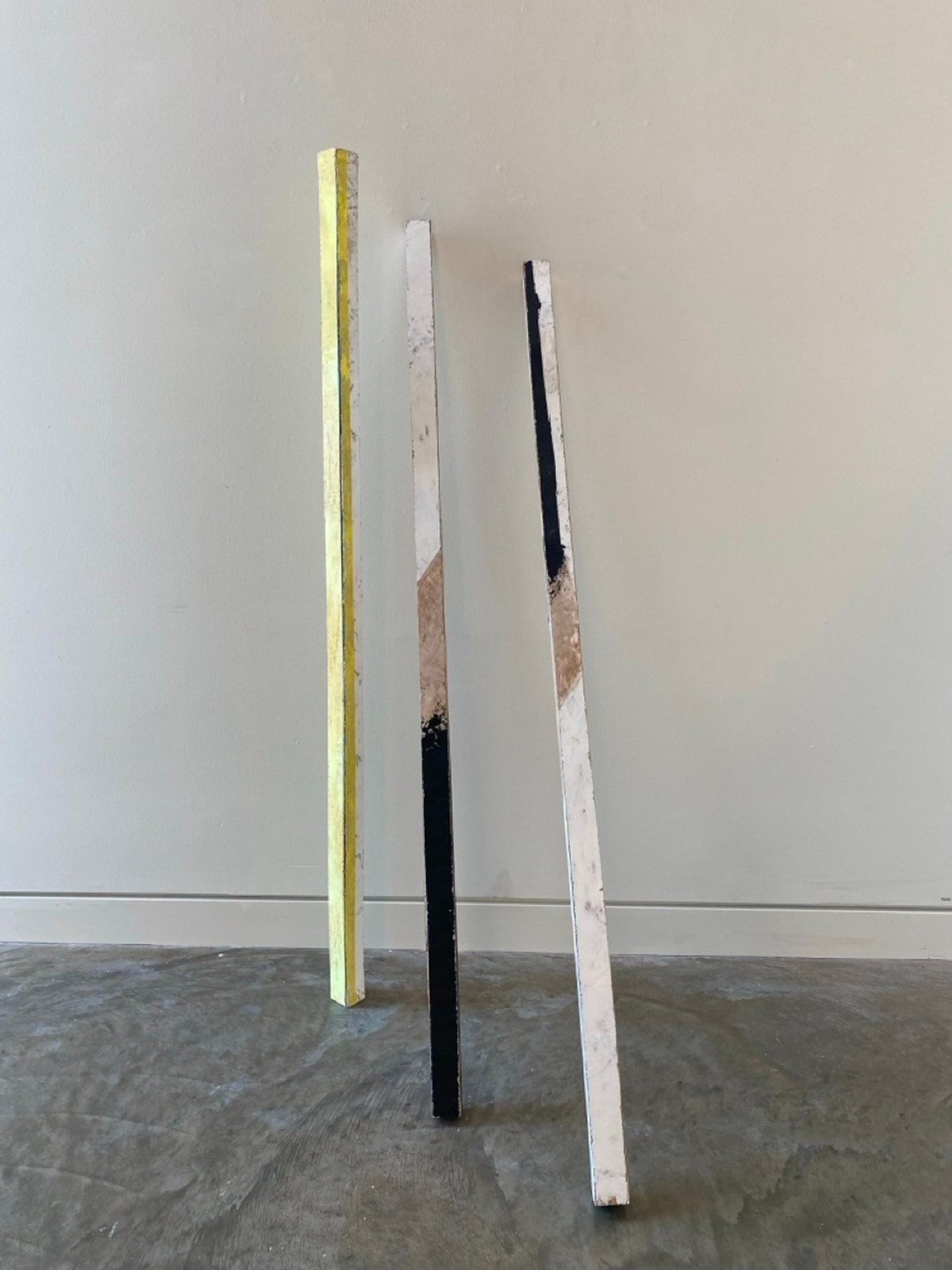 three long poles leaning against a wall