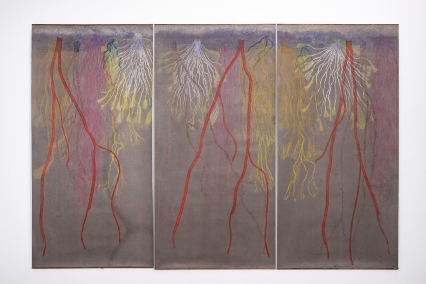 triptych of roots printed in reds, yellows, and oranges