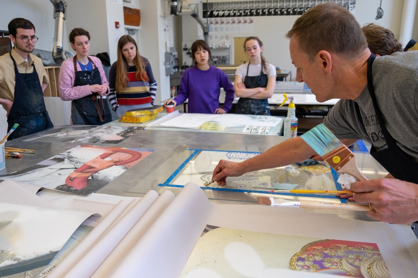 Group of people watch as a person demonstrates drawing on a plexi plate with a crayon.