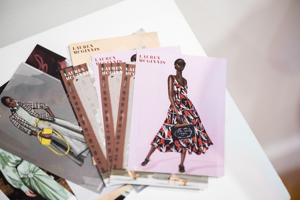 Plinth with a handful of postcards printed with fashion illustrations and "Lauren McGinnis."