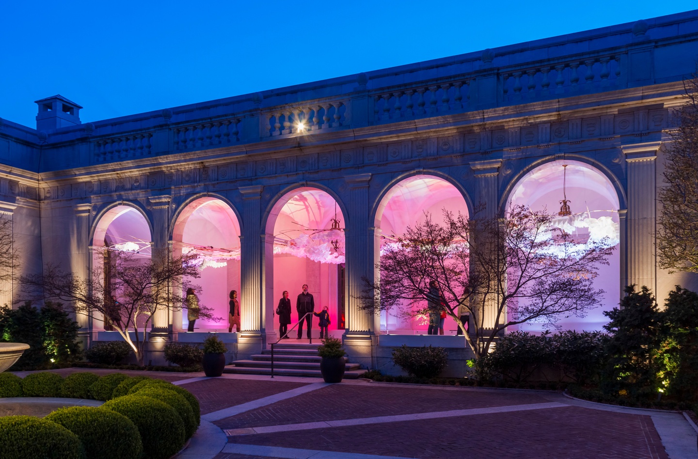 photo at night of building with people standing under the archways and different colorful lanterns