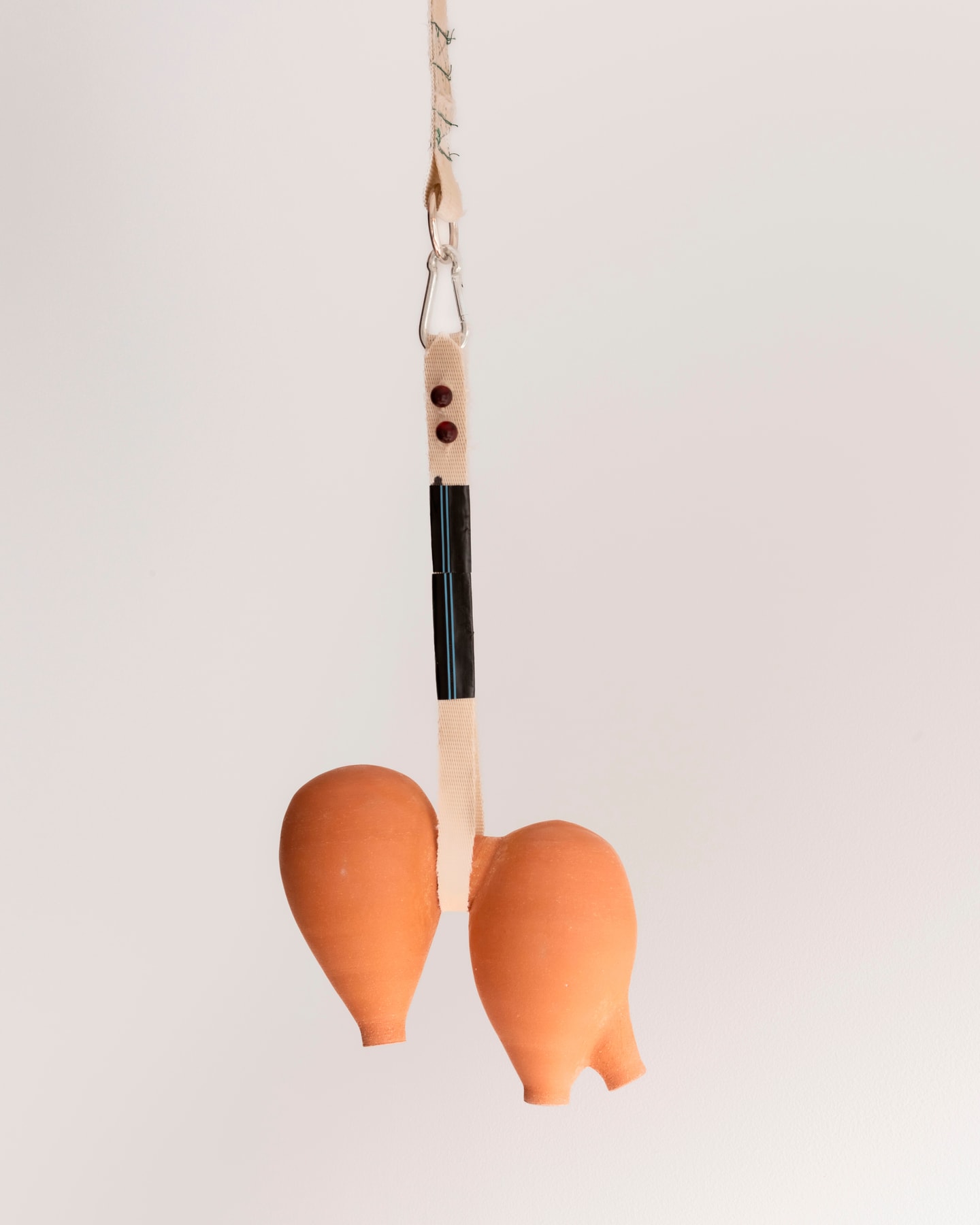 Sculpture of two fruit hanging made from ceramics and fire hose