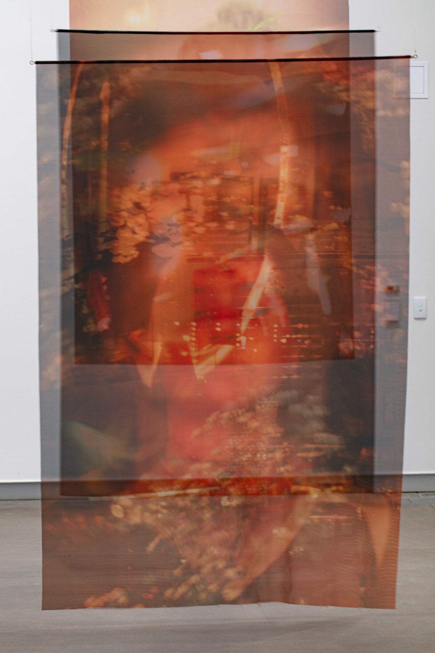 3 large scale photo prints on fabric hanging from the ceiling in a gallery