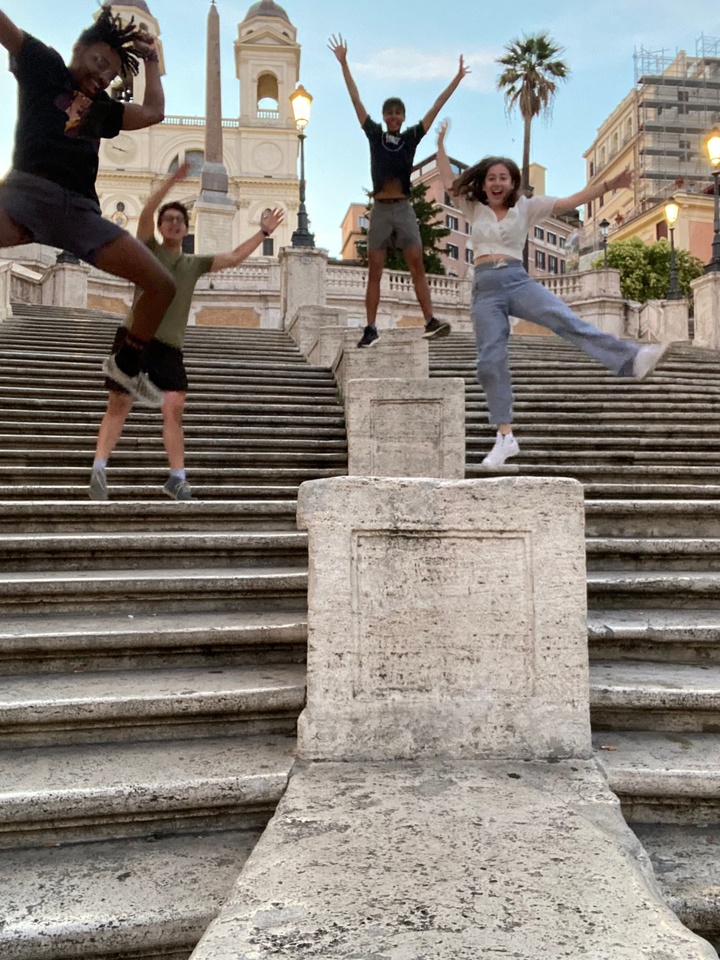 four students jumping on grand staircase