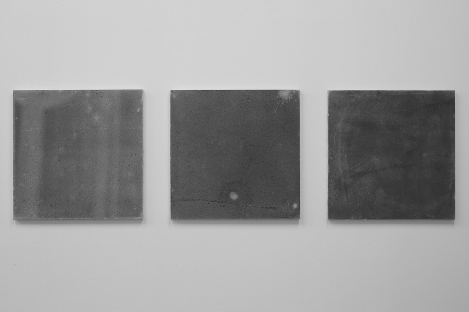 Three gray, square canvases, increasing in darkness from left to right